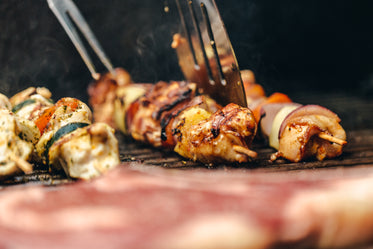 flipping chicken and veggie kabob on grill