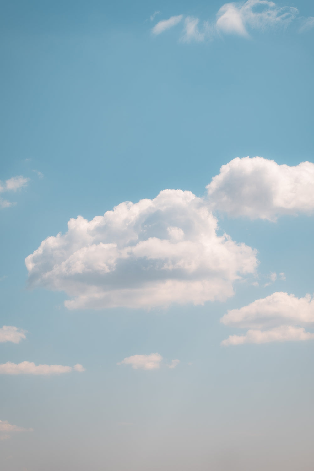 fluffy clouds in a light blue sky on a clear summer day