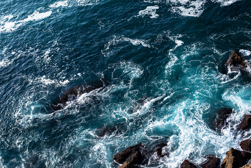 foaming blue water rolls over rocks