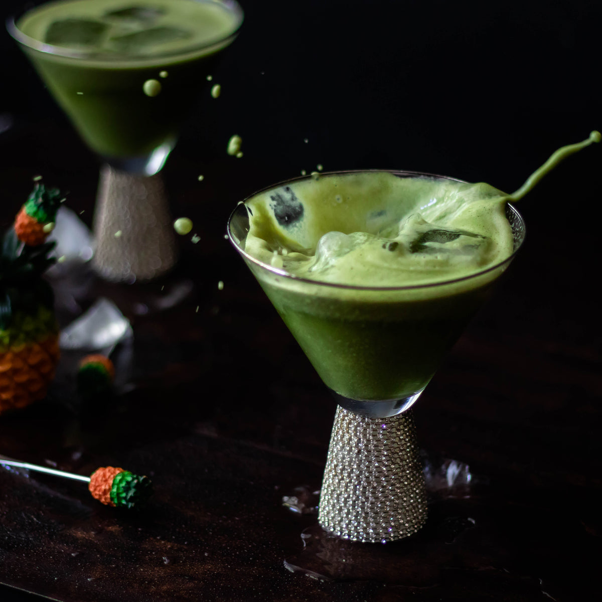 foamy green drink splashes in cocktail glass