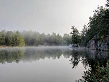 fog lingers over calm lake