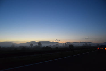foggy hillside by highway at sundown