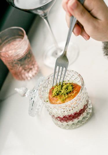 fork dips into a dessert in a crystal container