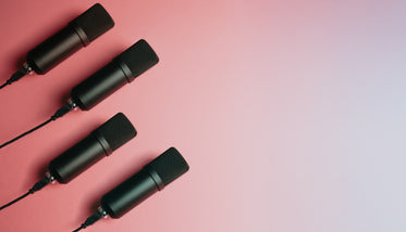 four black microphones lay on a pink background