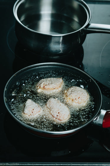 four breaded balls are being fried in oil