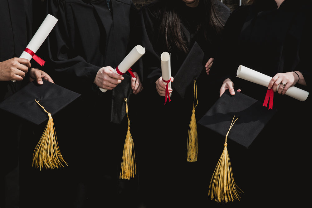 four grad students caps and diplomas
