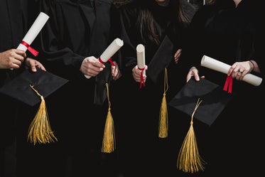 quatro estudantes com seus capelos e diplomas