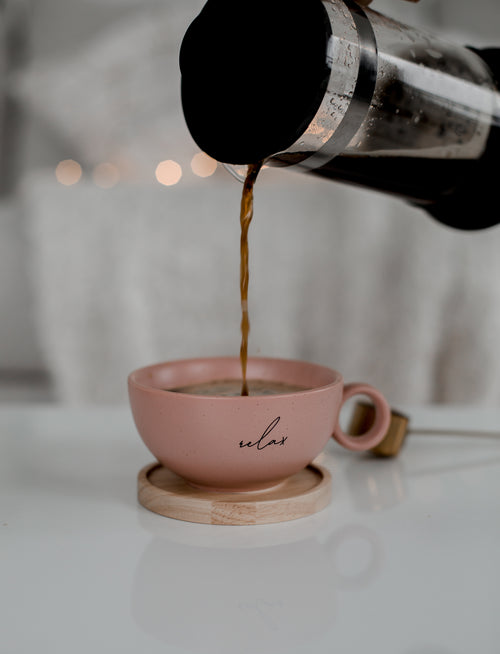 french press pours coffee into a pink coffee mug