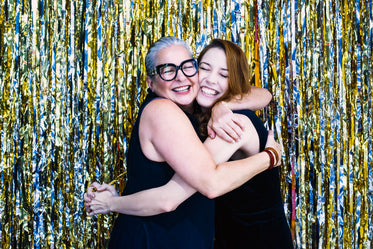 friends hug in front of silver and gold metallic streamers