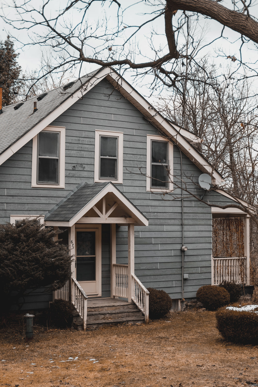 front of a light blue home on a winter day