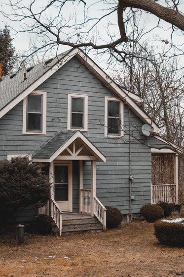 front of a light blue home on a winter day