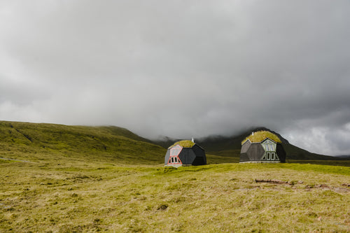 geodesic homes nestled in thick fog on grassy hillside