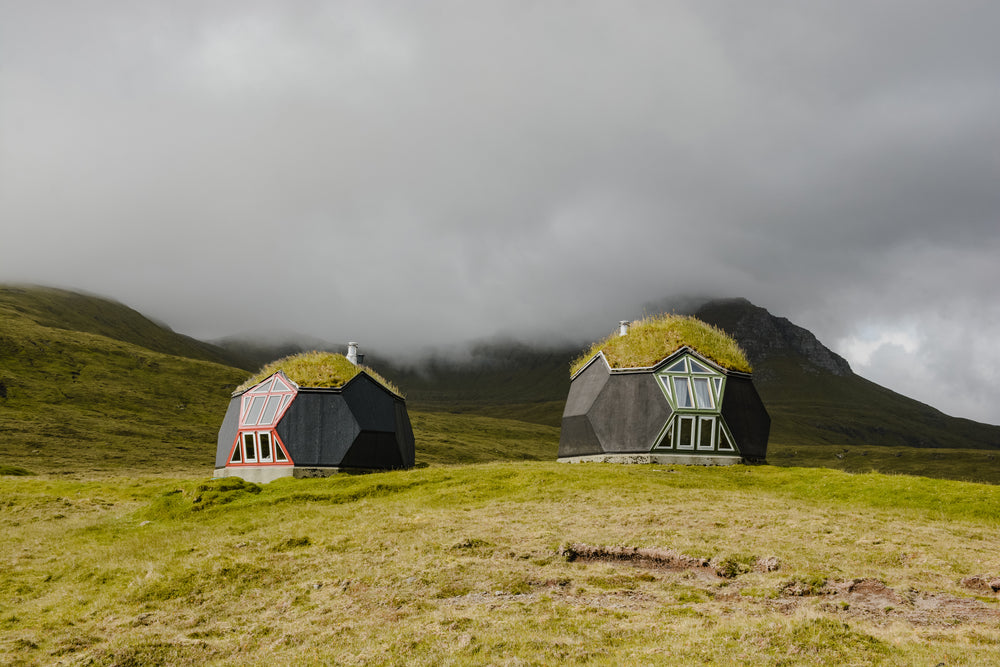 geodesic homes on grassy hilltop under fluffy cloud cover