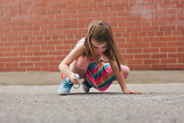 girl using sidewalk chalk in schoolyard