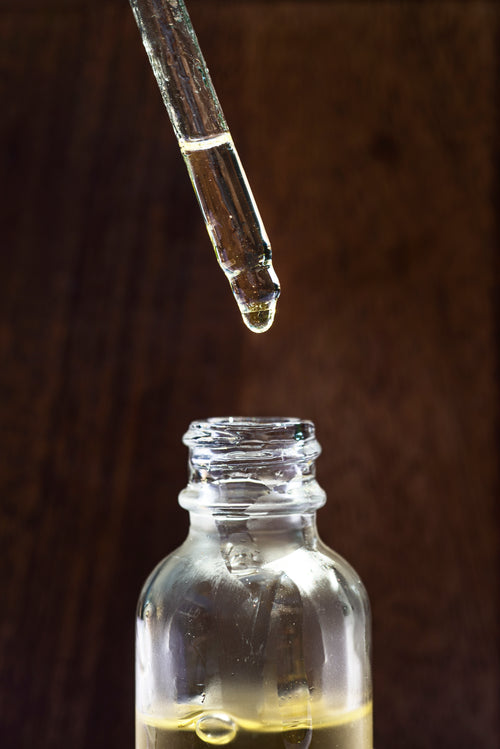 glass jar of face oil and a dropper above it