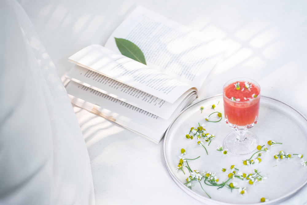 glass with a pink drink in it on a white plate