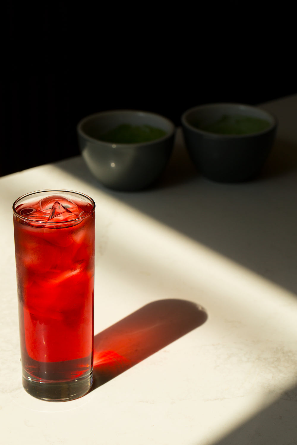 Glass With Iced Red Beverage Reflects On A White Table