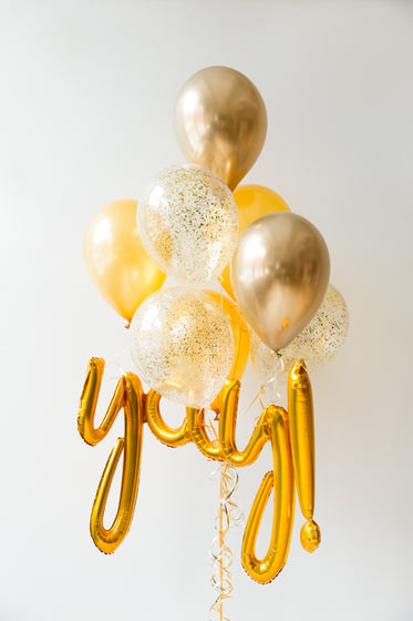gold helium balloons on white wall