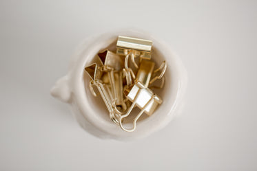 gold paper clips in a white bowl
