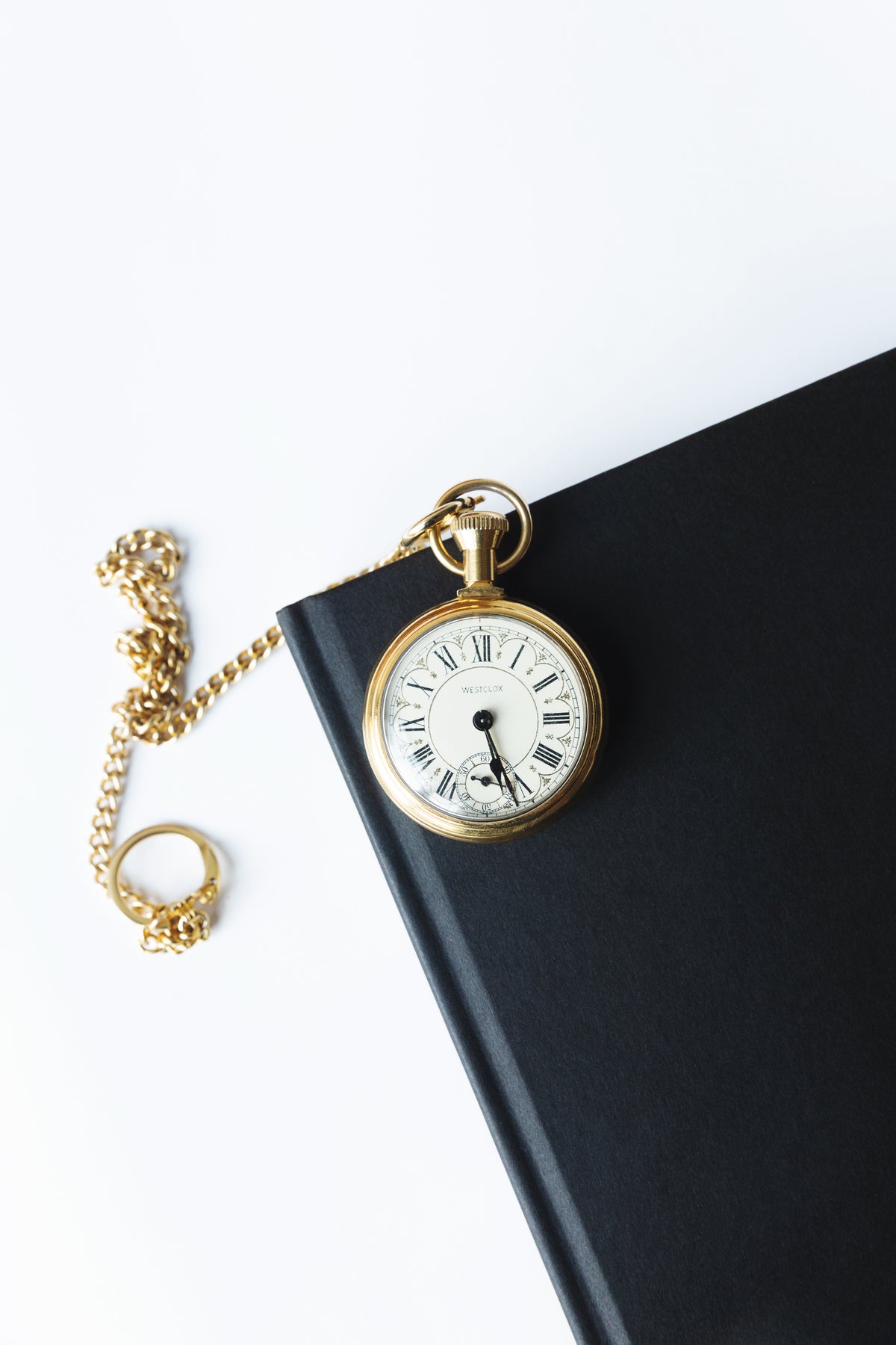 gold pocket watch on a black notebook