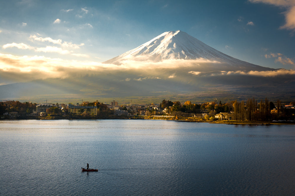 golden hour hits a snow capped mountain by a still lake