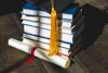 grad cap diploma and books stacked