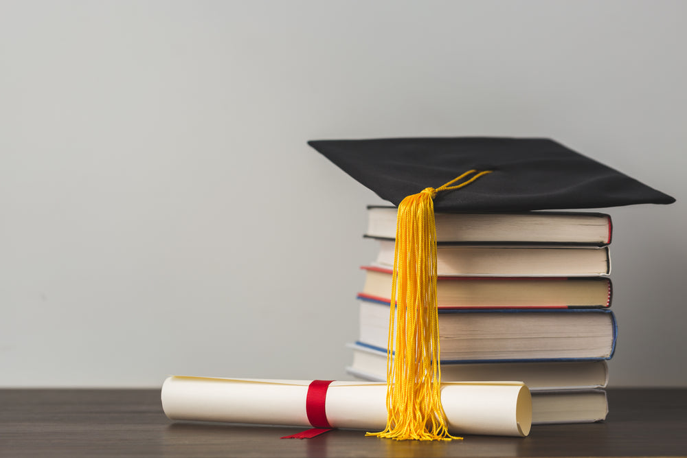 grad cap diploma and stacked books