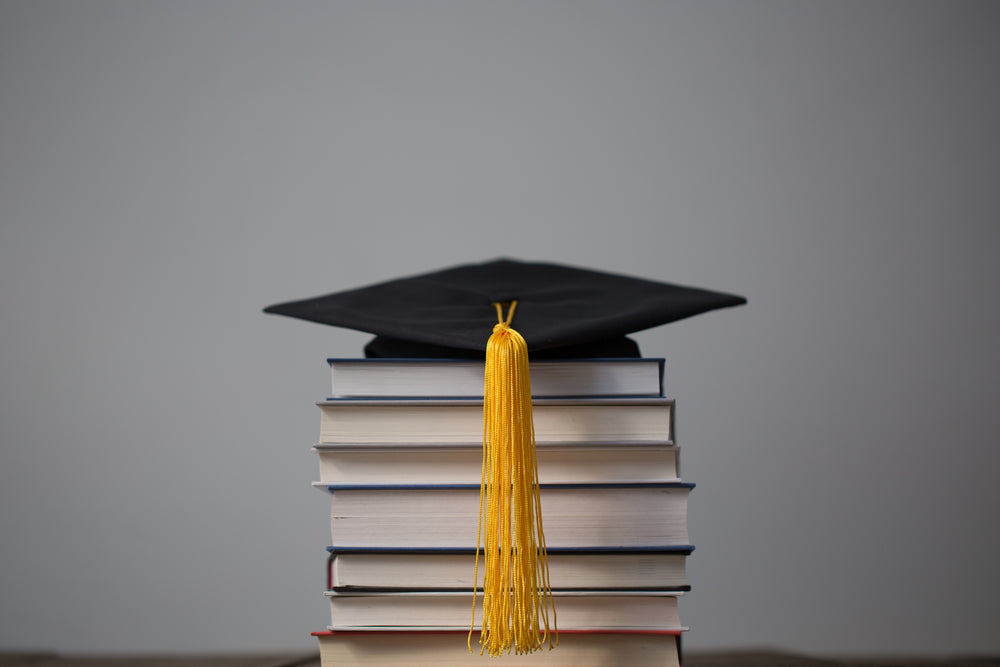 graduation cap on top of books