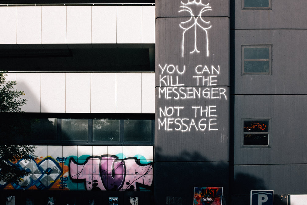 graffiti reads "you can kill the messenger, not the message"