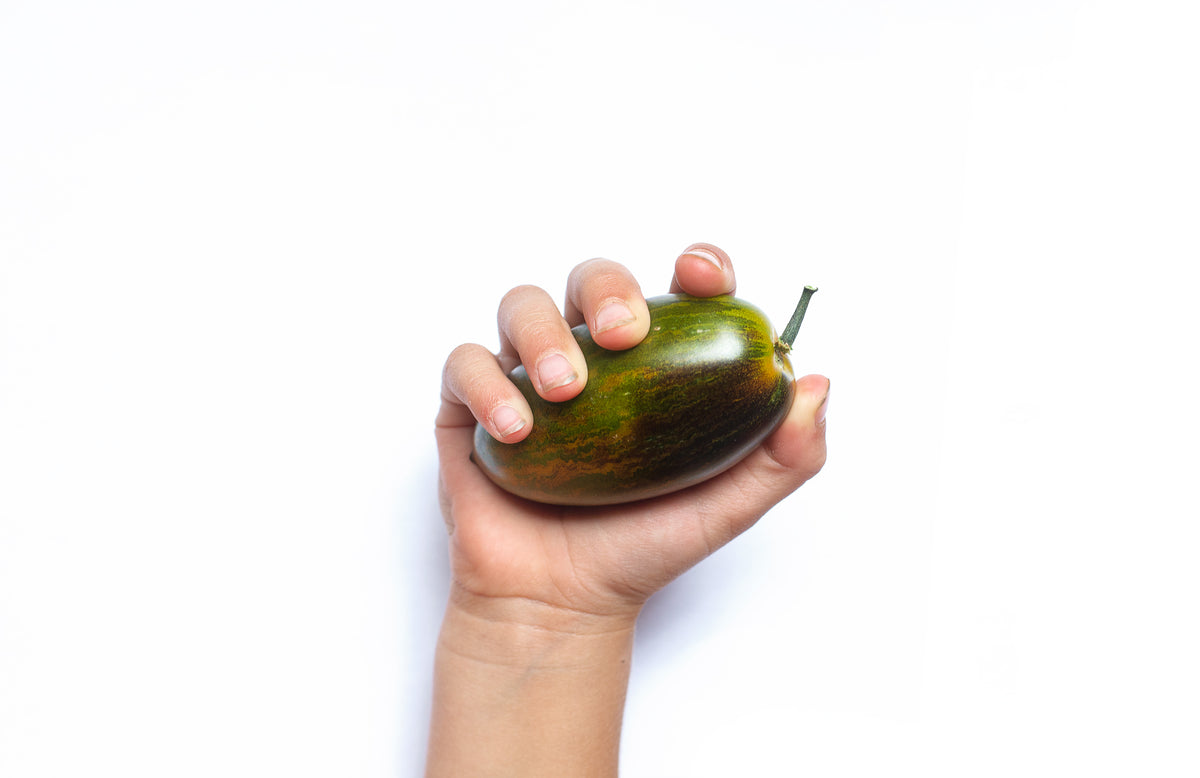green and brown fruit in hand