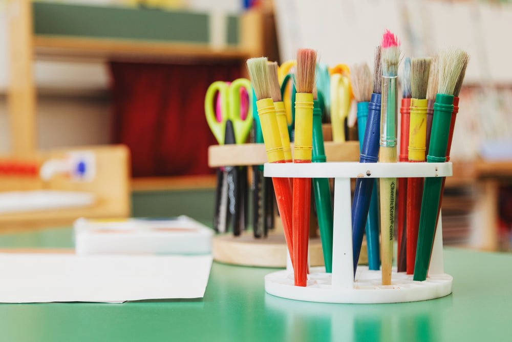 green craft table with scissors and paint brushes