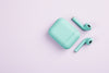 green earbuds and case on white surface
