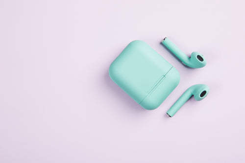 green earbuds and case on white surface
