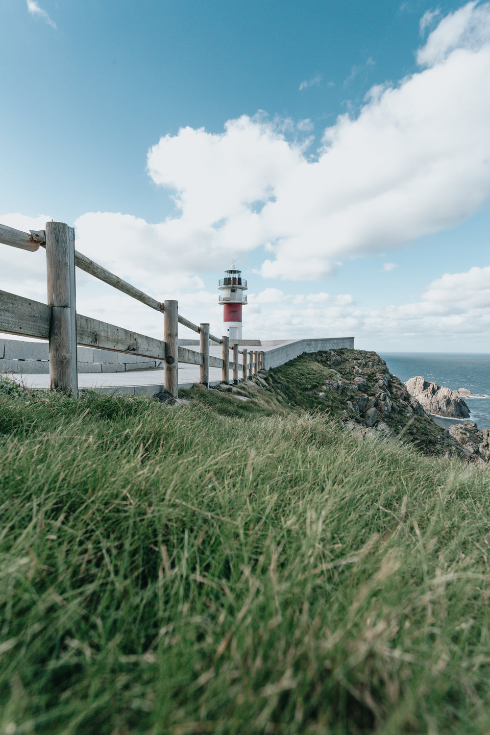 green grass and a wooden fence with a lighthouse behind it