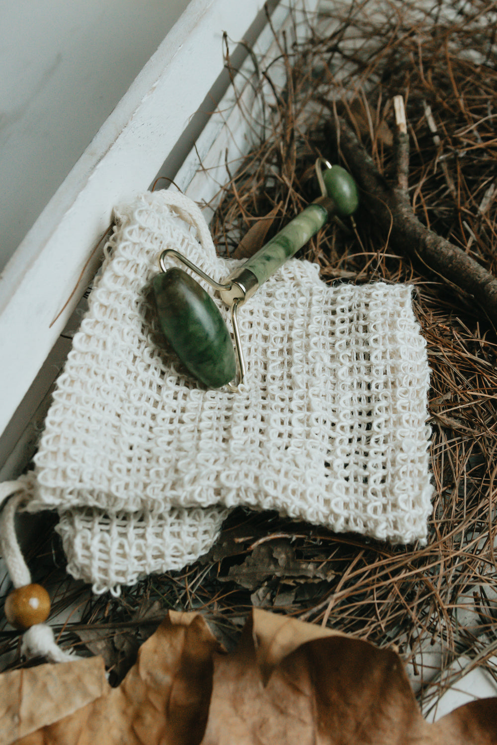 green jade roller on a white mesh cloth