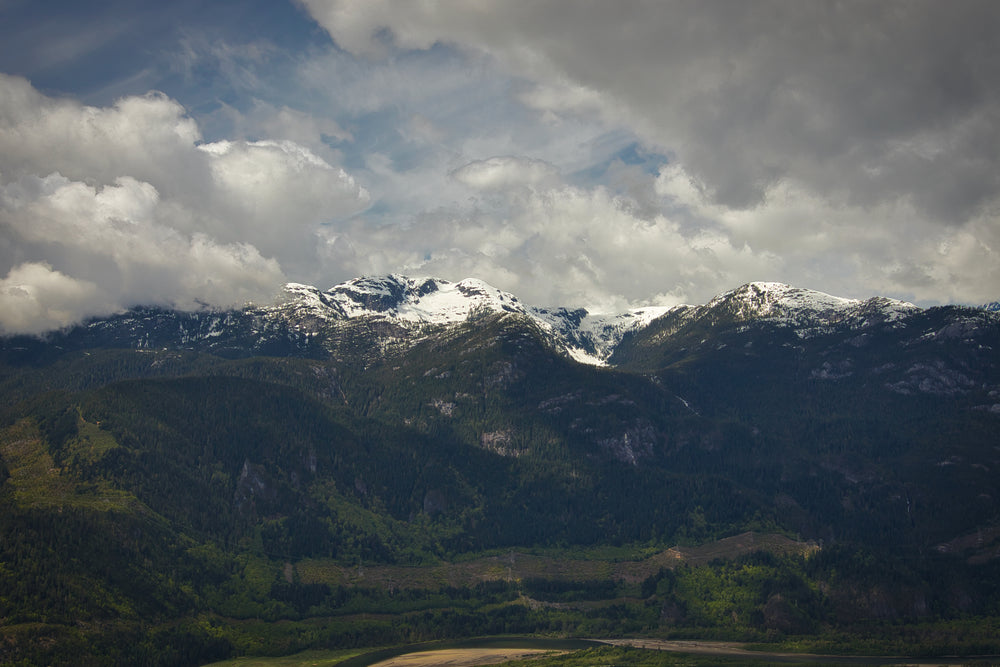 green mountains covered in snow under fluffy clouds