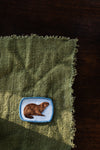 green piece of fabric with beaver patch sewn in place