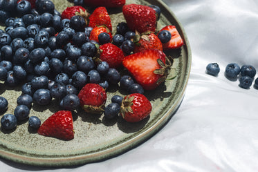 green plate with fresh berries on silk