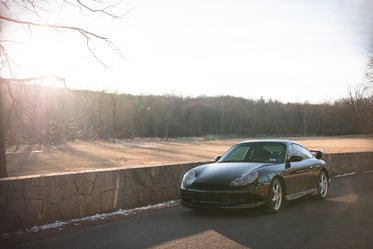 grey car is parked by a stone wall