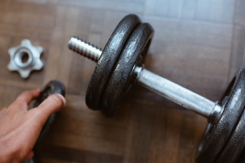 hand adding more weight to a dumbbell