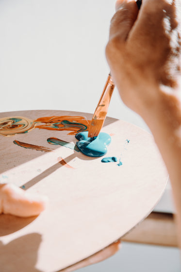 hand dips paint brush into paint pallet