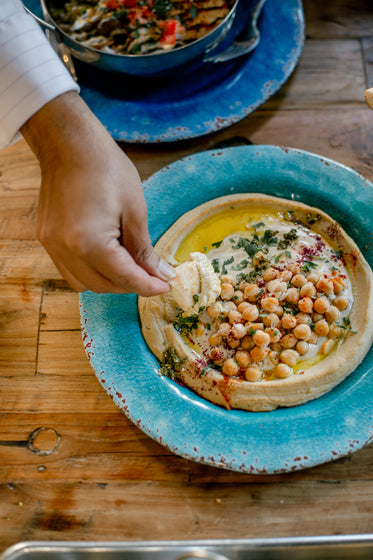 hand dips pita in hummus