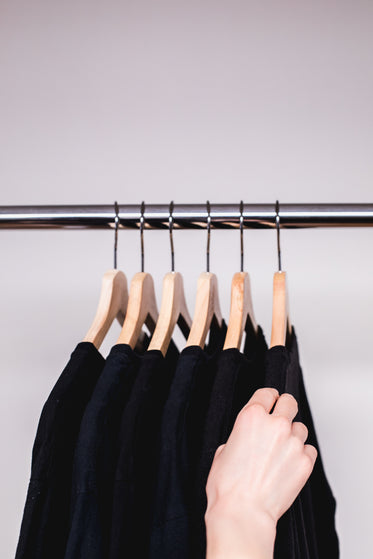 hand flicks through clothes on a rack