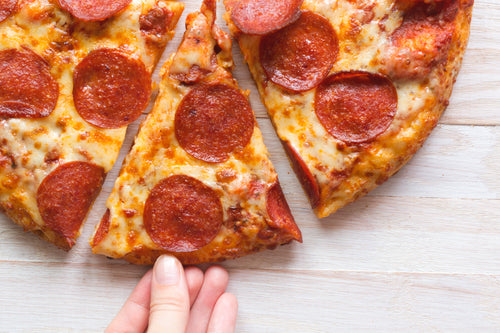 hand grabbing a hot slice of pizza