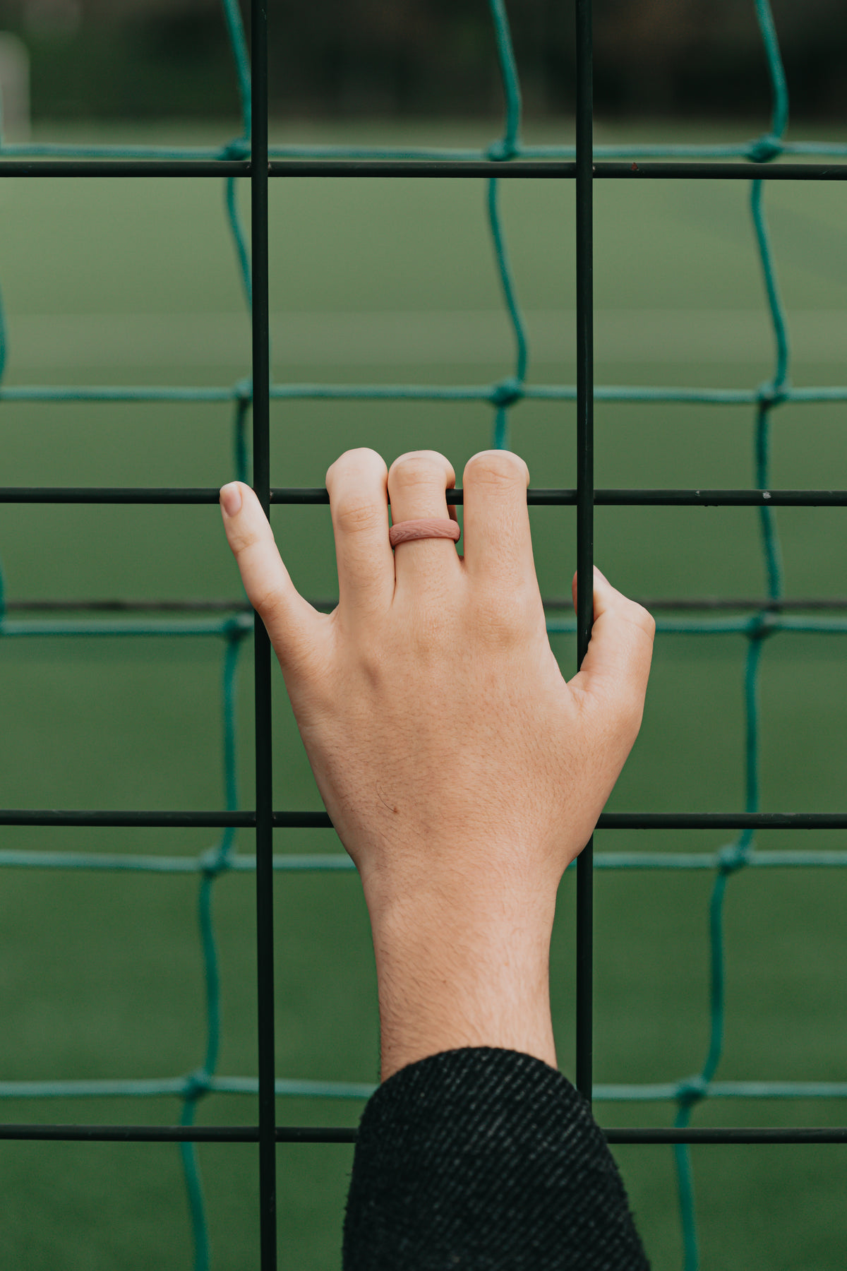 hand grasping a black fence