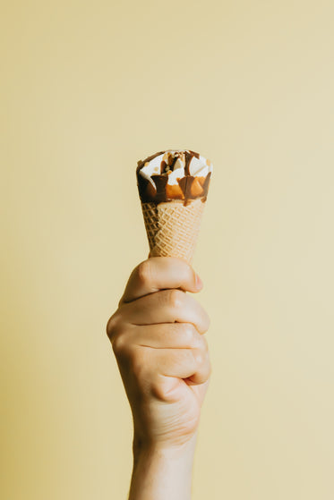 hand grips a chocolate dripped ice cream cone