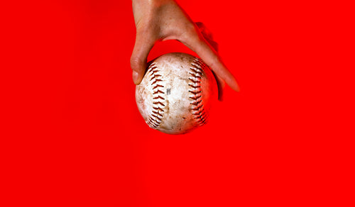 hand holding baseball on red