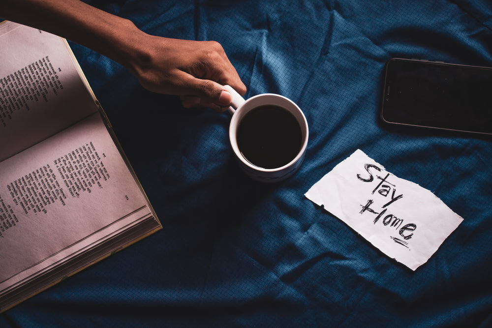 hand holding coffee near book and phone.