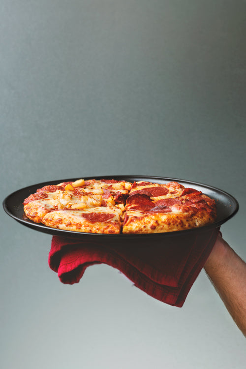 hand holding oven cooked pizza