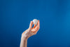 hand holding ping pong ball on blue background